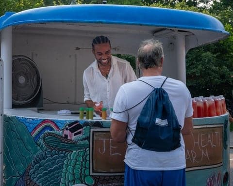 Vendor pouring fresh juice from a market food truck