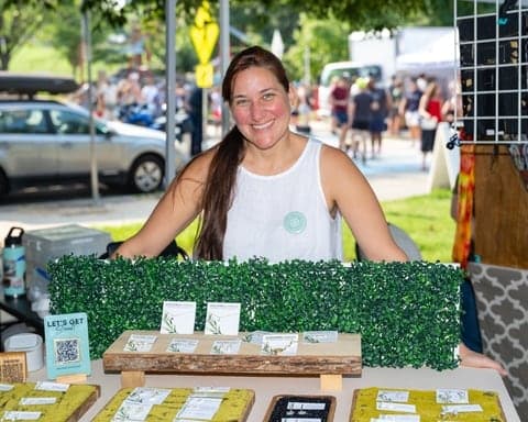 Vendor smiling behind her market stand of handmade candles