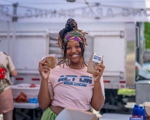 Vendor holding up market treats, all smiles