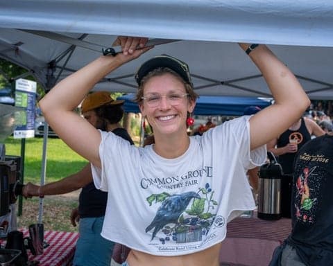 Vendor laughing under a market tent